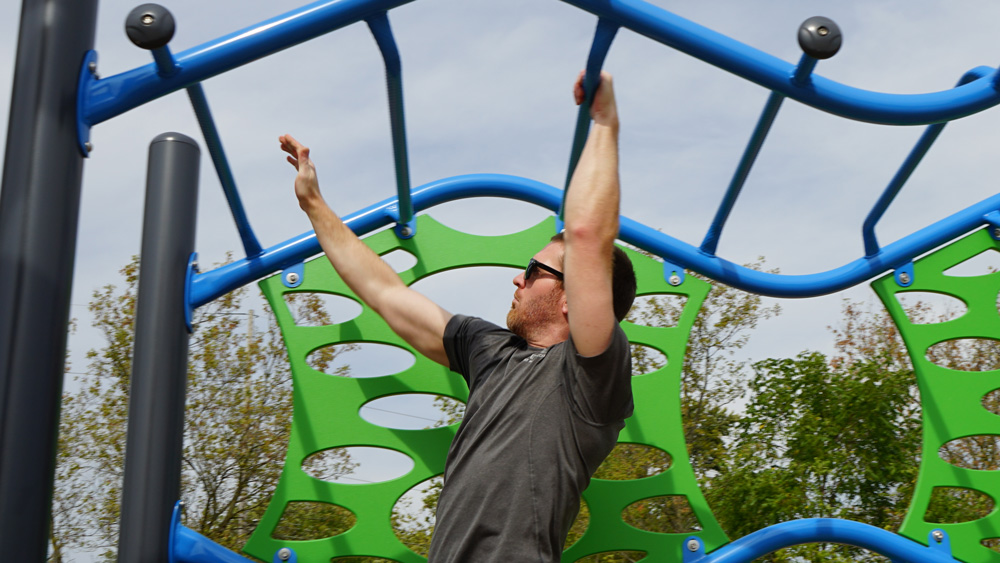 man with sunglasses playing on monkey bars